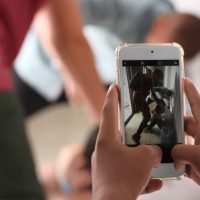 Teenager taking video of bullying boy with mobile phone at school, closeup